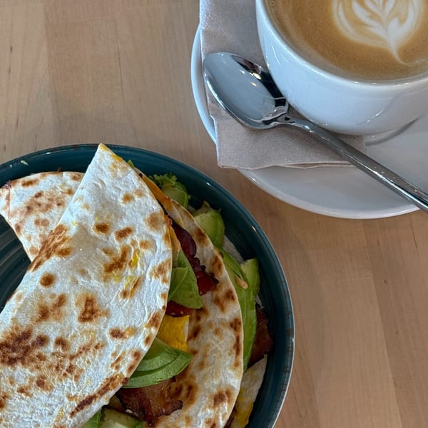 Sunny Cafe's breakfast tacos with avocado, bacon, and egg, alongside a latte with art.