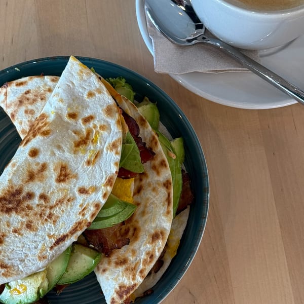 Sunny Cafe's quesadilla with avocado, bacon, and cheese, served with a coffee.