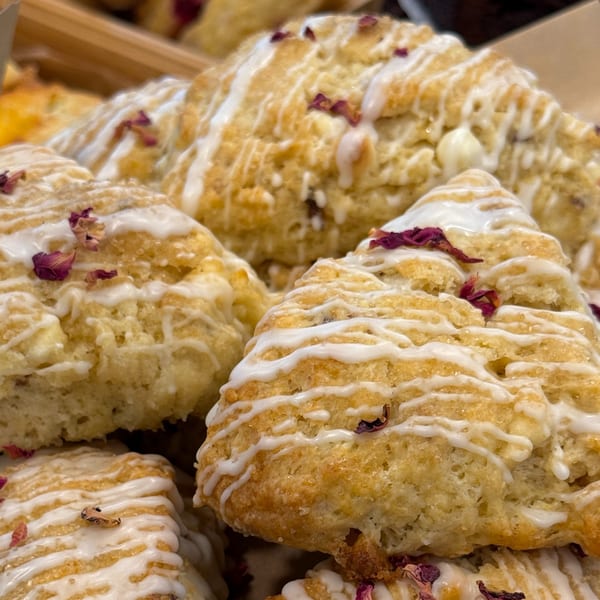 Close-up of Sunny Cafe scones with white icing and dried rose petals.