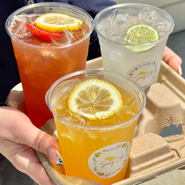 Three iced drinks from Sunny Cafe, one red with lemon and strawberry, one clear with lime, and one yellow with lemon.