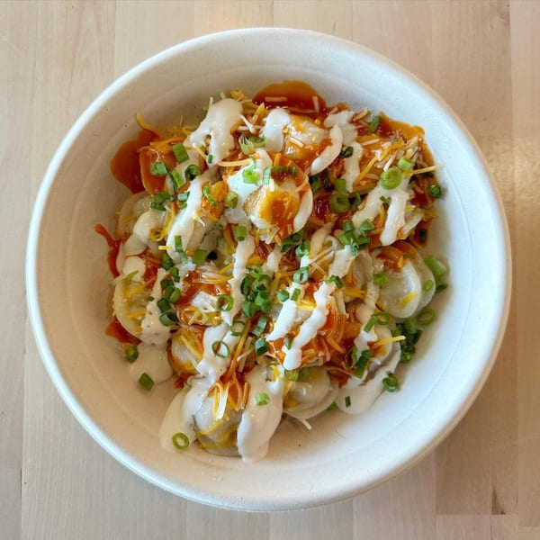 Sunny Cafe's pierogi bowl with sour cream, hot sauce, shredded cheese, and green onions.
